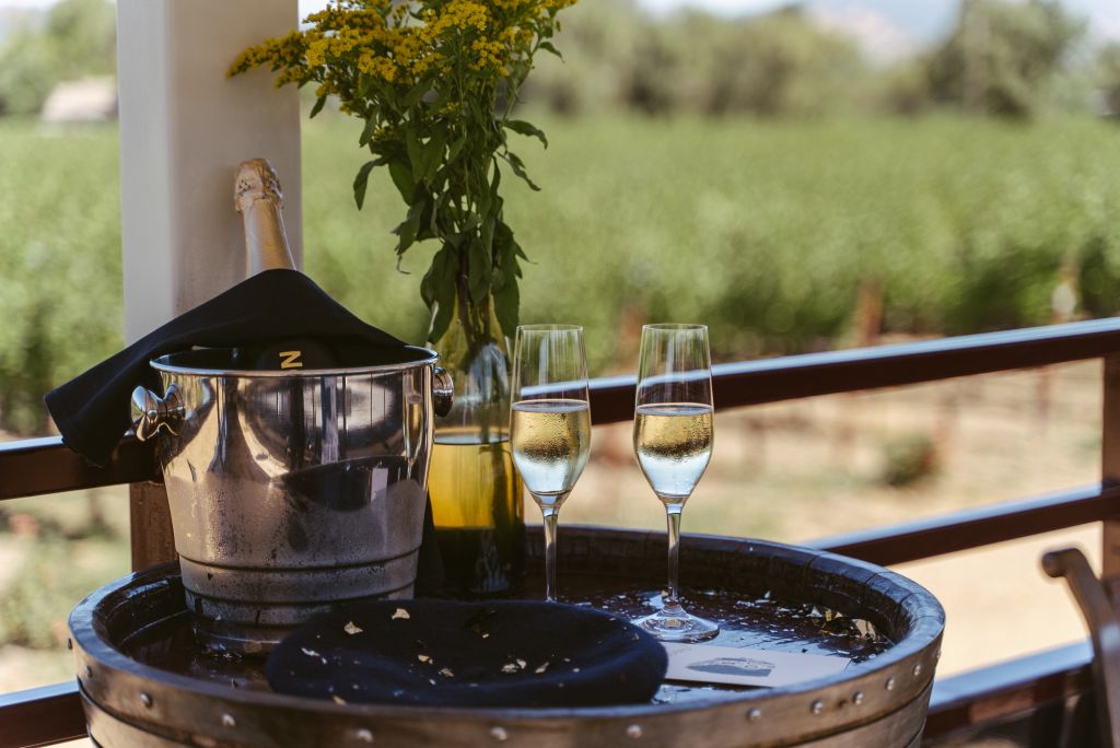 Champagne in an ice bucket with two flutes of champagne beside it.